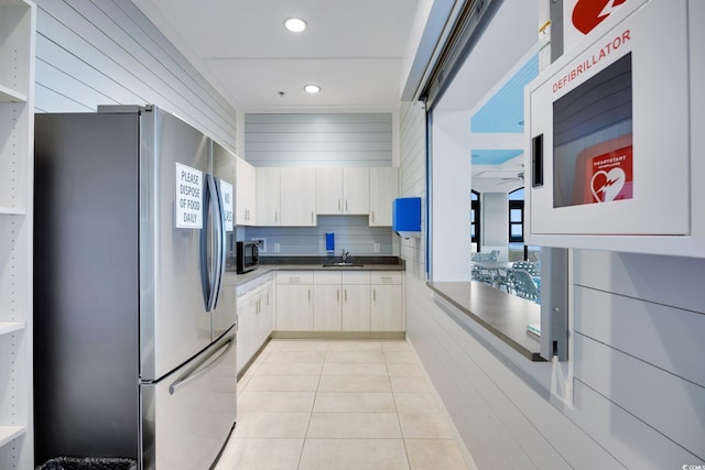 kitchen featuring light tile patterned flooring, recessed lighting, stainless steel appliances, a sink, and dark countertops