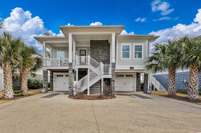 coastal home featuring a porch, board and batten siding, stone siding, driveway, and stairs