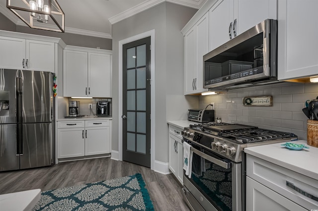 kitchen featuring ornamental molding, light countertops, appliances with stainless steel finishes, and white cabinets