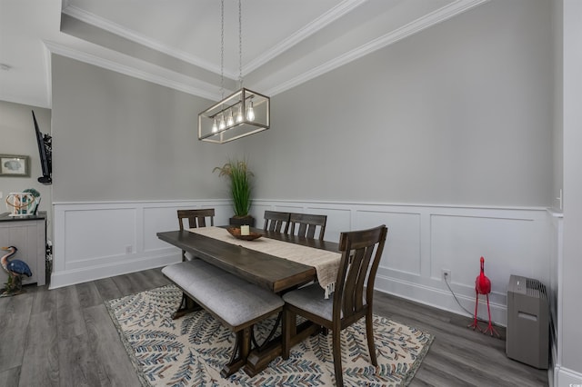 dining area with ornamental molding, wainscoting, wood finished floors, and a decorative wall