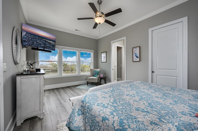 bedroom with ceiling fan, wood finished floors, visible vents, baseboards, and ornamental molding