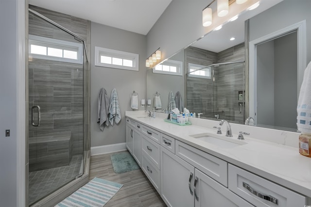 full bath featuring a sink, a shower stall, baseboards, and double vanity