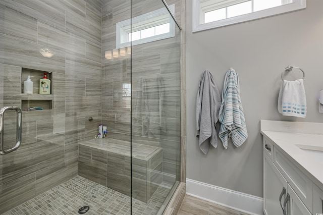 bathroom with a stall shower, vanity, and baseboards