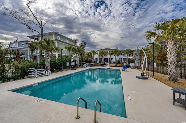 community pool with a patio area and fence