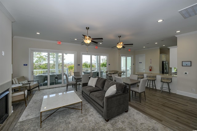 living area with crown molding, visible vents, wood finished floors, and recessed lighting