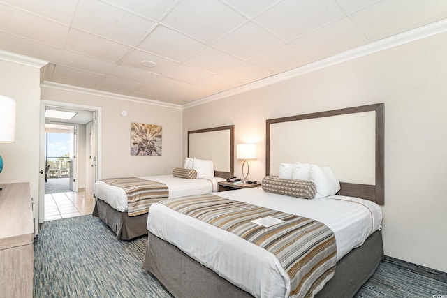 carpeted bedroom with ornamental molding and a drop ceiling