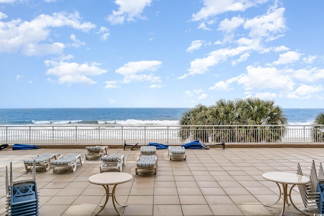 view of patio with a water view and a beach view