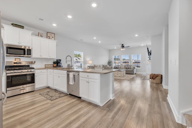 kitchen with stainless steel appliances, recessed lighting, white cabinets, a sink, and a peninsula