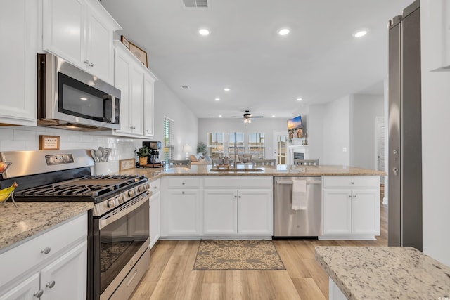 kitchen with stainless steel appliances, a ceiling fan, light wood-style flooring, and white cabinetry