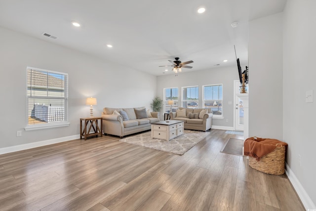 living room featuring light wood finished floors, baseboards, visible vents, a ceiling fan, and recessed lighting