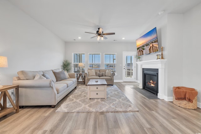 living area with baseboards, a ceiling fan, a fireplace with flush hearth, light wood-style floors, and recessed lighting