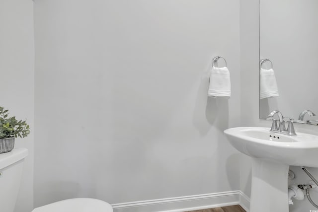 half bath featuring toilet, baseboards, and wood finished floors