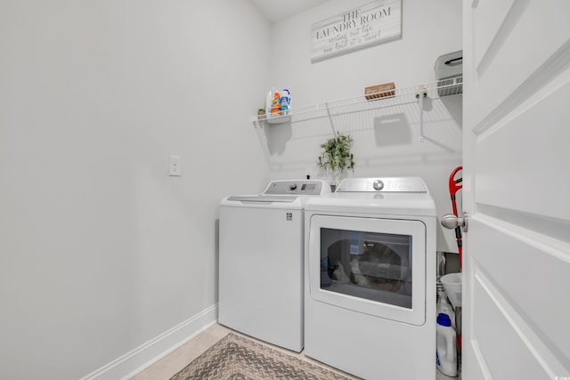 clothes washing area with laundry area, baseboards, and separate washer and dryer