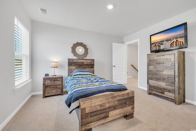 bedroom featuring visible vents, light carpet, and baseboards