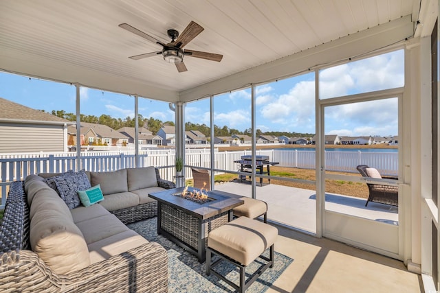 sunroom featuring ceiling fan, a water view, and a residential view