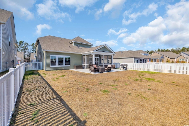 back of property featuring a lawn, a sunroom, a patio area, a residential view, and a fenced backyard