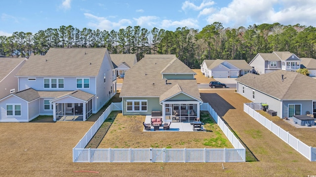 rear view of property featuring a lawn, a sunroom, a patio area, a residential view, and a fenced backyard