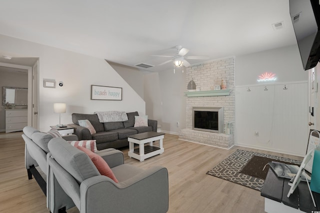 living room with a fireplace, wood finished floors, visible vents, and a ceiling fan