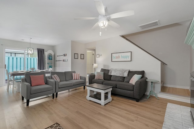 living area with baseboards, light wood-style flooring, visible vents, and a ceiling fan