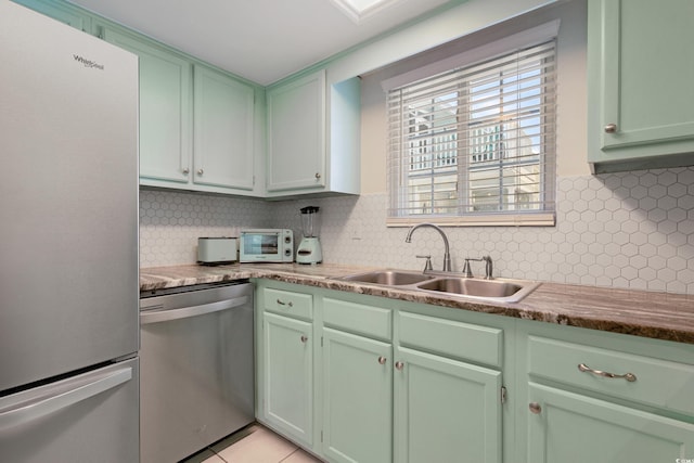 kitchen featuring appliances with stainless steel finishes, a sink, backsplash, and green cabinets