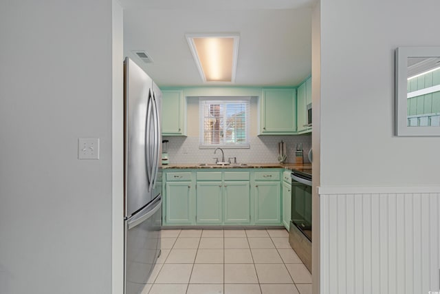 kitchen with a sink, visible vents, green cabinetry, and freestanding refrigerator