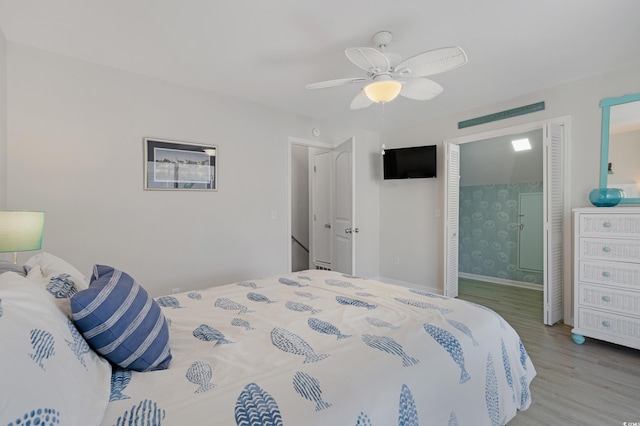 bedroom featuring a ceiling fan, ensuite bathroom, baseboards, and wood finished floors