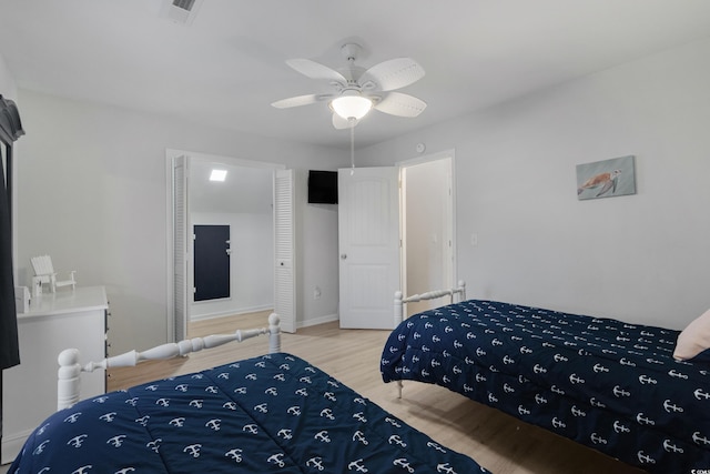 bedroom featuring a ceiling fan, visible vents, baseboards, and wood finished floors