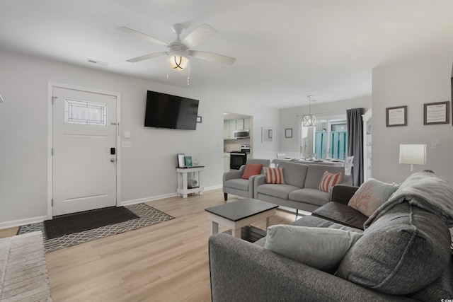 living area featuring light wood finished floors, a healthy amount of sunlight, visible vents, and baseboards