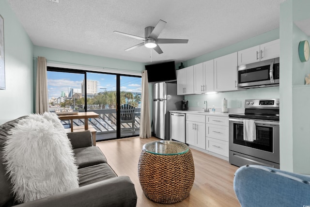 kitchen featuring a sink, light countertops, white cabinets, appliances with stainless steel finishes, and light wood-type flooring