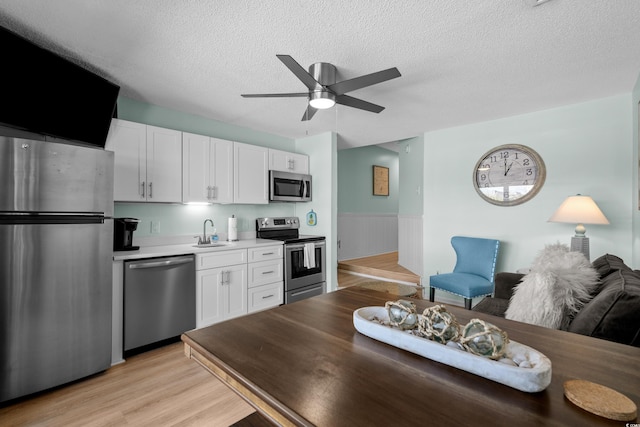 kitchen featuring appliances with stainless steel finishes, white cabinetry, light countertops, and a sink