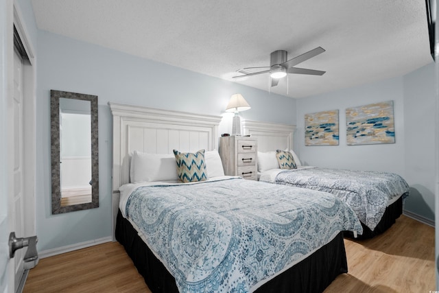 bedroom with ceiling fan, baseboards, a textured ceiling, and wood finished floors