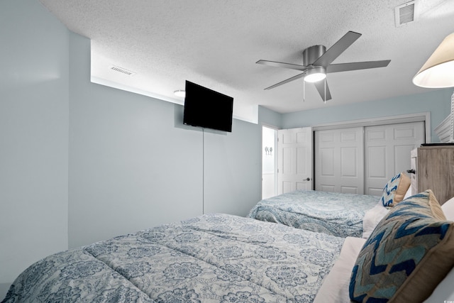 bedroom with a ceiling fan, visible vents, a closet, and a textured ceiling