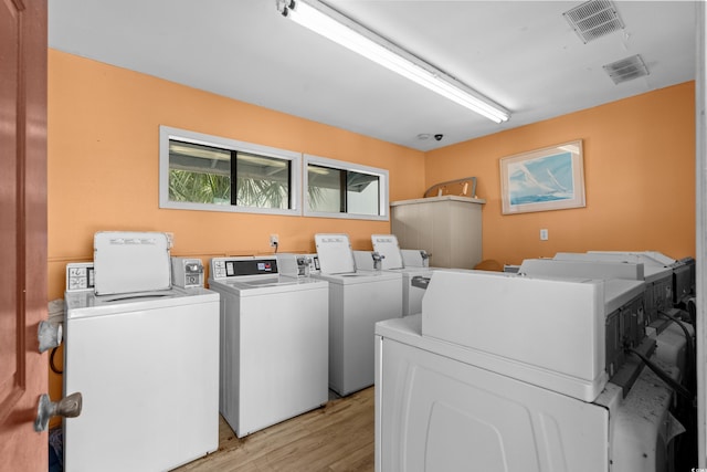 shared laundry area with visible vents, washing machine and dryer, and light wood finished floors