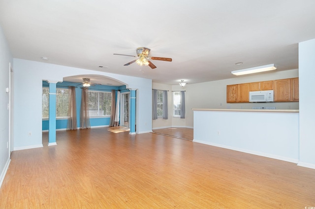 unfurnished living room featuring light wood-style floors, ornate columns, baseboards, and a ceiling fan