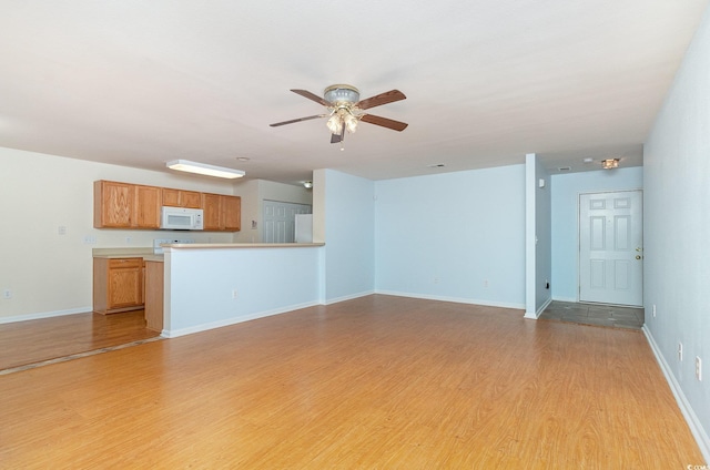 unfurnished living room featuring light wood-style floors, ceiling fan, and baseboards