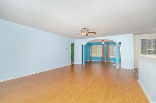 spare room with light wood-type flooring, baseboards, arched walkways, and a ceiling fan