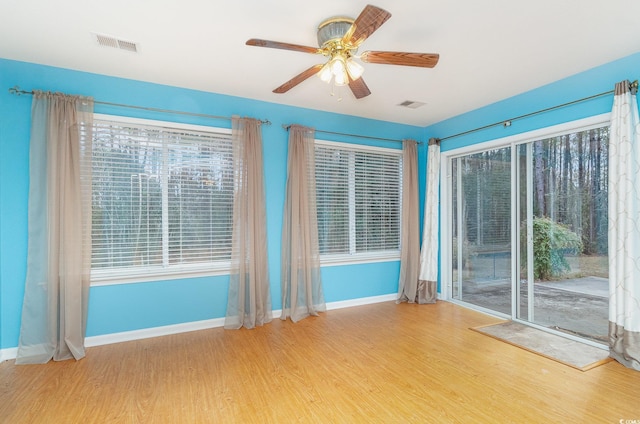 unfurnished room with a ceiling fan, baseboards, visible vents, and wood finished floors