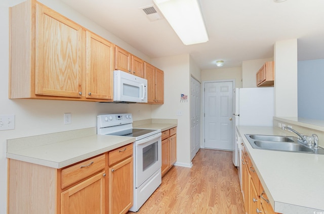 kitchen featuring light wood finished floors, visible vents, light brown cabinetry, a sink, and white appliances