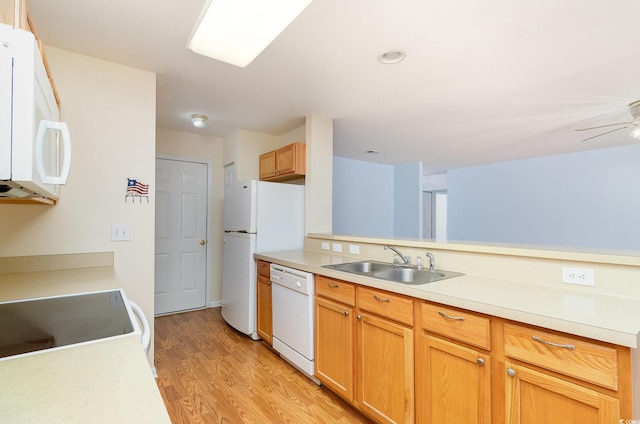 kitchen featuring white appliances, light countertops, a sink, and light wood finished floors