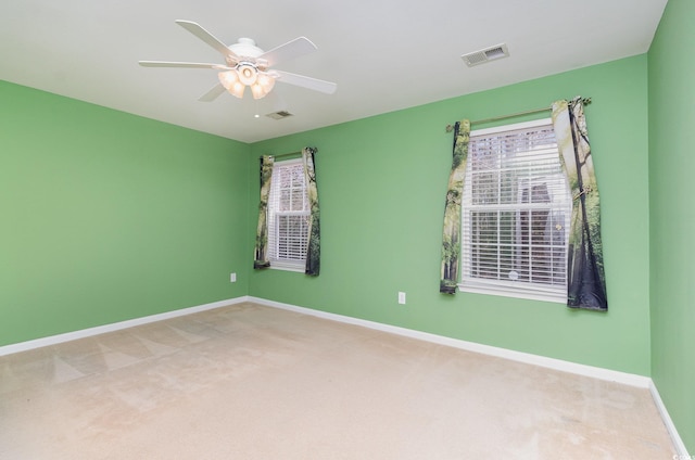 carpeted empty room featuring baseboards, visible vents, and a ceiling fan