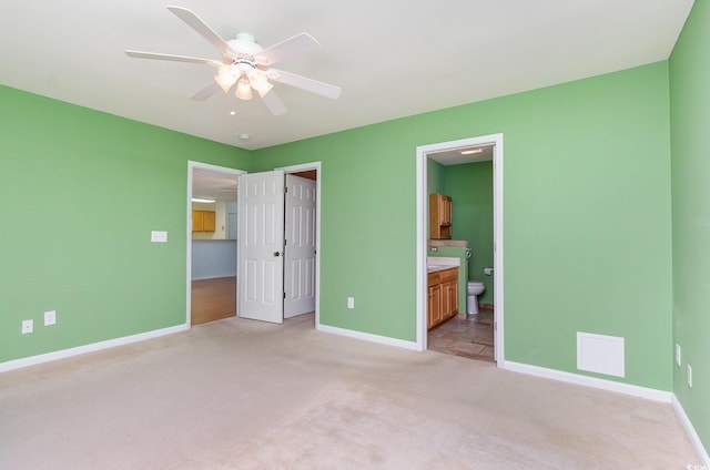 unfurnished bedroom with light carpet, ceiling fan, baseboards, and ensuite bathroom