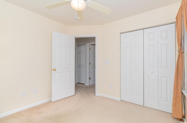 unfurnished bedroom with light carpet, a closet, a ceiling fan, and baseboards