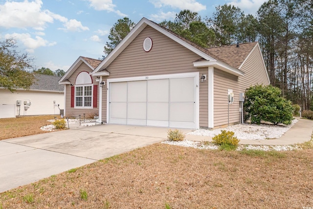 single story home with an attached garage, driveway, a front yard, and roof with shingles