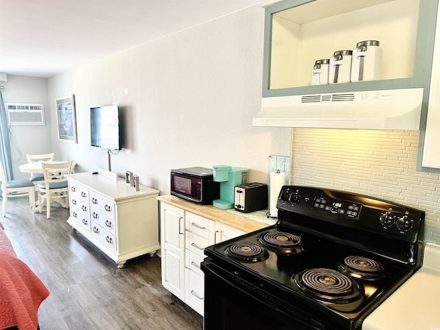 kitchen with a wall mounted air conditioner, black appliances, under cabinet range hood, wood finished floors, and light countertops