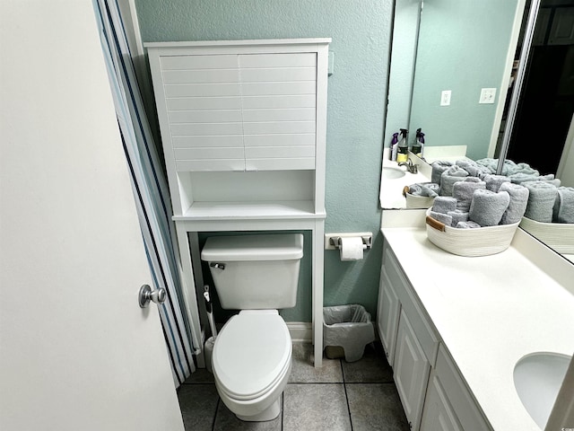 bathroom with toilet, vanity, and tile patterned flooring