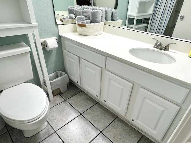 bathroom with vanity, tile patterned floors, toilet, and a textured wall