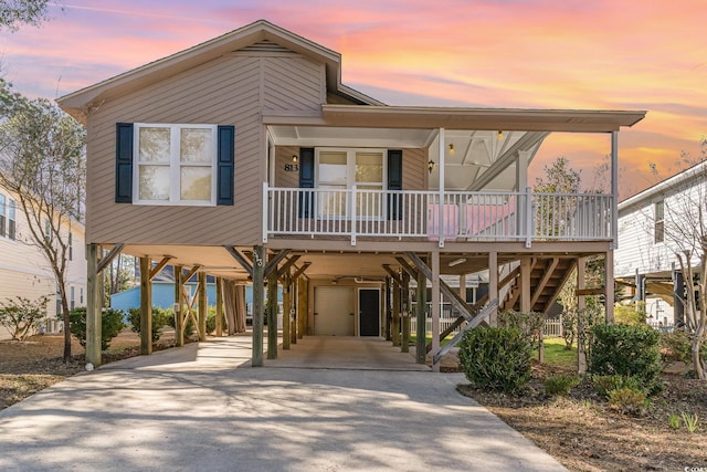 raised beach house with a carport, a porch, stairway, and driveway