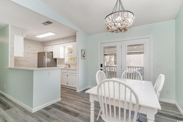 dining area featuring baseboards, a textured ceiling, visible vents, and light wood-style floors