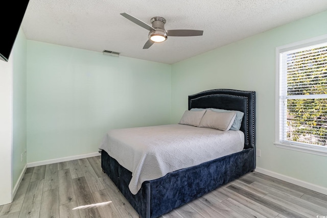 bedroom with wood finished floors, visible vents, and baseboards