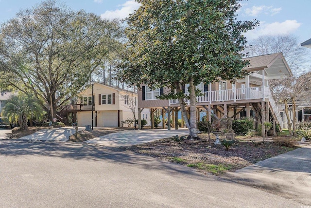 coastal inspired home featuring a garage, concrete driveway, and a porch